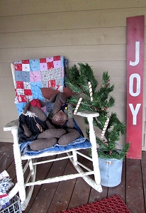 An old quilt and a pair of stuffed moose adorn an ancient rocker.  Paul and Shelia painted the 'Joy' sign on old barn siding a couple of years ago.  Click for bigger photo.
